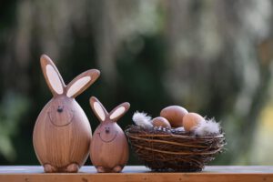 Charming wooden bunny figurines beside a nest of eggs, perfect for Easter decor.